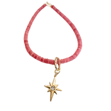 Gold North Star charm with crystal center hanging from a pink beaded necklace on a white background.