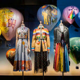 Mannequins wearing colorful outfits with decorative balloons in the background