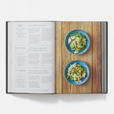 Open cookbook showing a recipe with two bowls of salad on a wooden surface