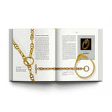 Open book displaying gold jewelry with a visible Hermes logo