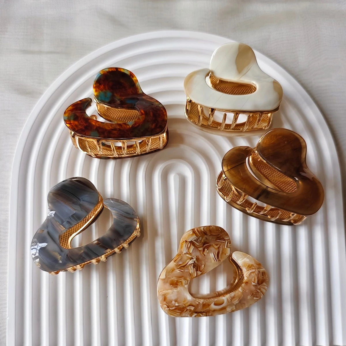 Set of five decorative hair claws on a textured white surface