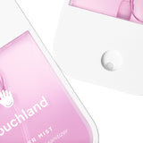 Pink and white bottle ofouchland hand sanitizer with a droplet on a white background