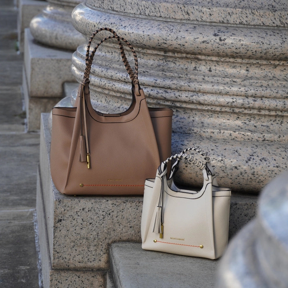 Two handbags, one brown and one beige, on stone steps.