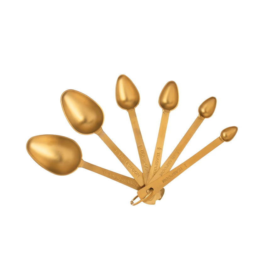 Set of gold measuring spoons on a white background
