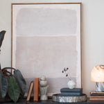 Framed abstract art piece on a wall with decorative items below