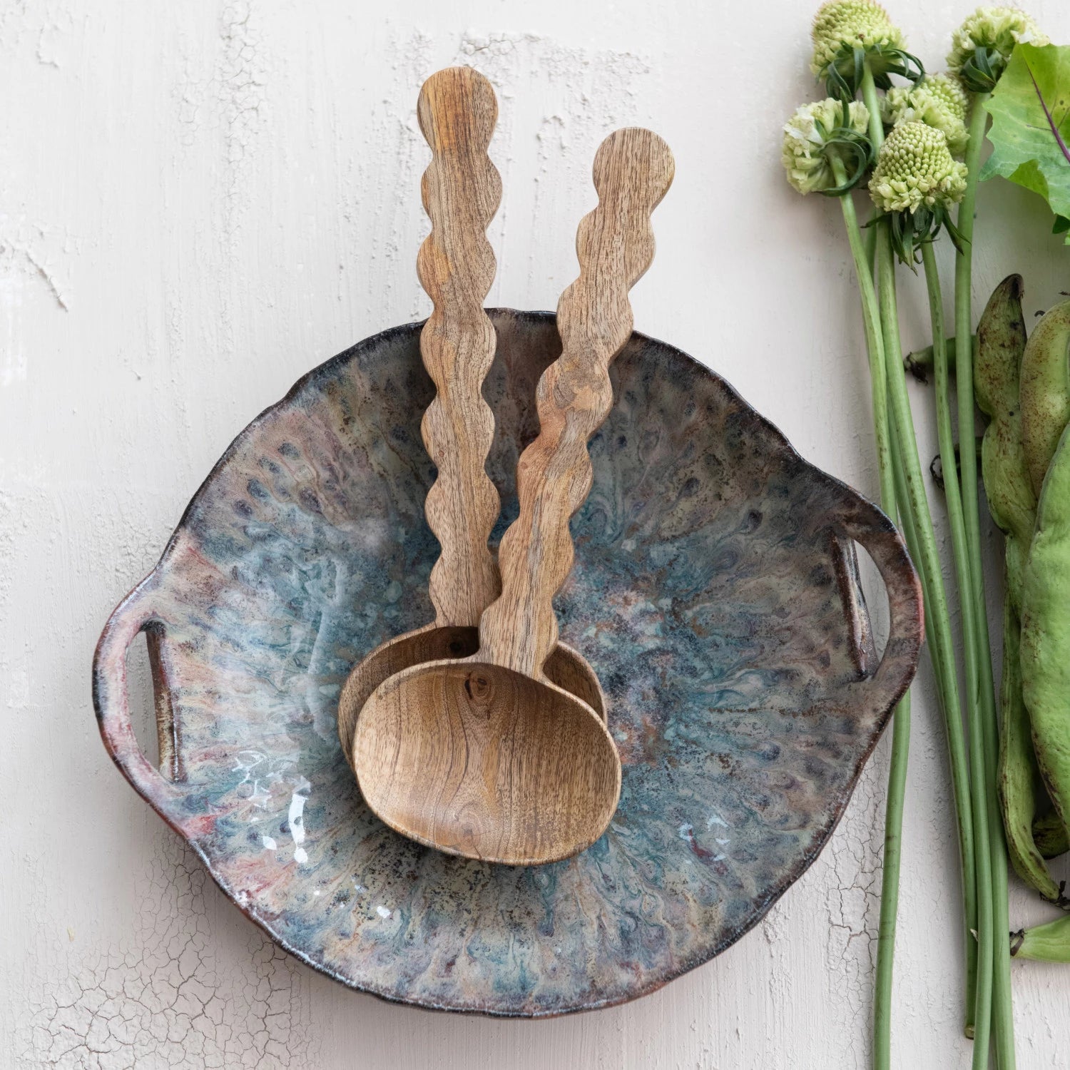 Wooden ladles on a ceramic plate with greenery on a light background
