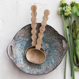 Wooden ladles on a ceramic plate with greenery on a light background