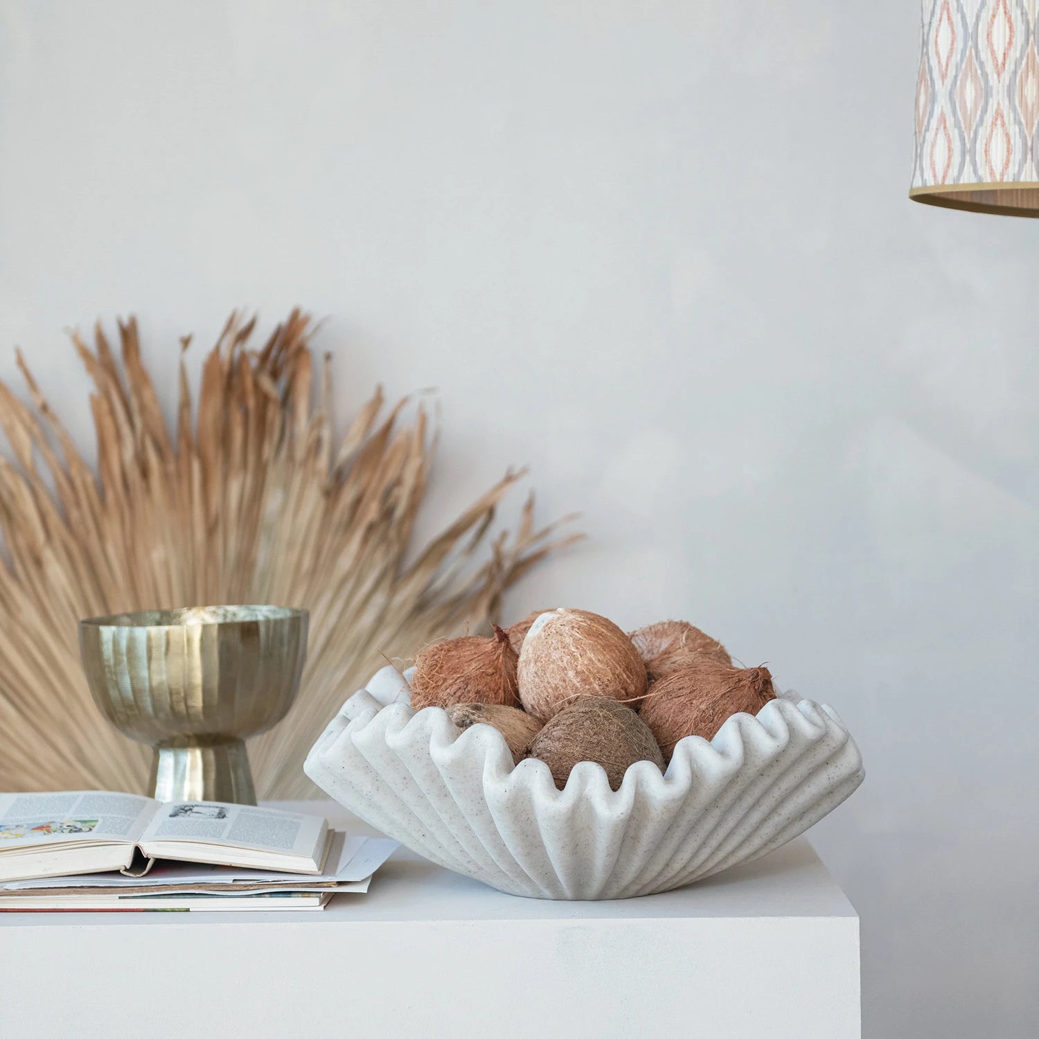 Decorative bowl with textured surface holding coconuts on a white surface with a neutral background