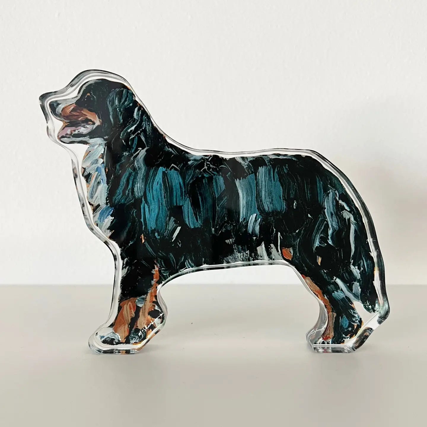 Dog-shaped glass paperweight with black, blue, and brown colors on a white background