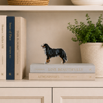 Decorative shelf with books, a dog figurine, and a plant.