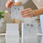Marriage prayer cards with artistic illustrations held by a person.