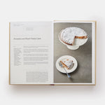 Open cookbook showing a recipe for Amaretto and Peach Pastry Cake with a slice of cake on a plate.
