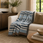 Blue and white striped blanket draped over a beige sofa in a living room setting.