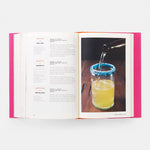 Open book with a page showing a cocktail recipe and another with a cocktail being poured into a glass.