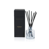 Aromatherapy diffuser with black sticks and clear container on a white background