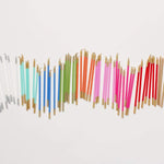 Colorful candles with gold holders arranged in a decorative pattern on a white background