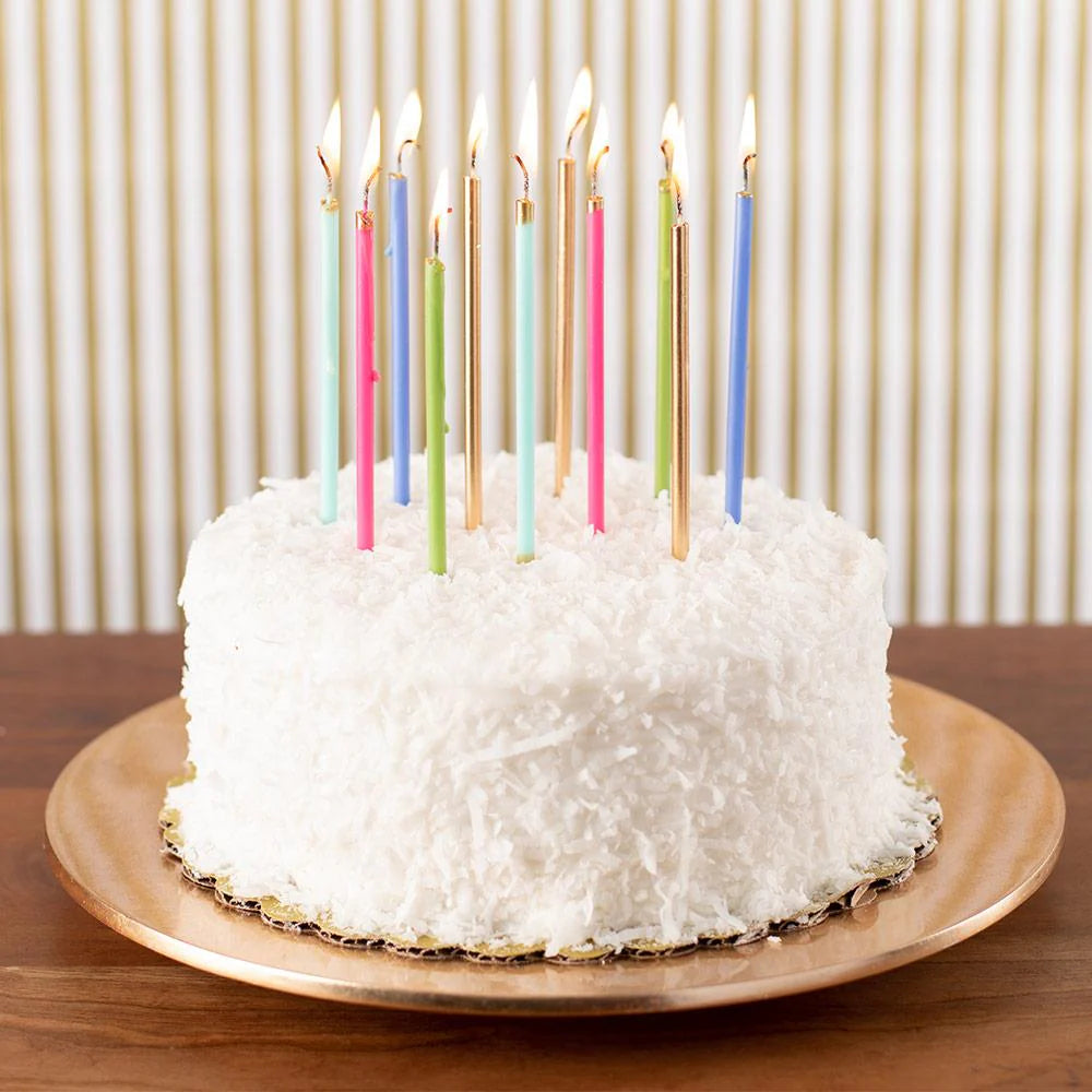 White cake with colorful candles on a wooden table