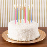 White cake with colorful candles on a wooden table