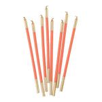 Set of coral candles with gold tips on a white background