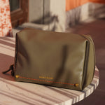 Montemare Roma Standing Toiletry Case in Olive on a marble surface.
