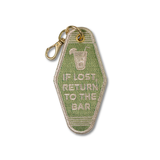 An embroidered vintage hotel room key keychain tag with a gold-tone lobster clasp. The tag has a textured sage green background with a white-outlined design featuring a cocktail glass icon and the text 'IF LOST RETURN TO THE BAR' in white.