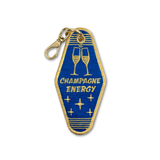 A vintage hotel room key embroidered keychain or bag charm in royal blue and gold, featuring two clinking champagne glasses and the text 'CHAMPAGNE ENERGY' with a gold lobster clasp attached at the top, shown on a plain white background.