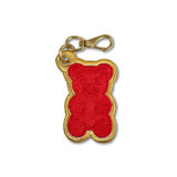 An embroidered red gummy bear keychain charm with a gold metallic border and a gold lobster clasp, shown on a plain white background.