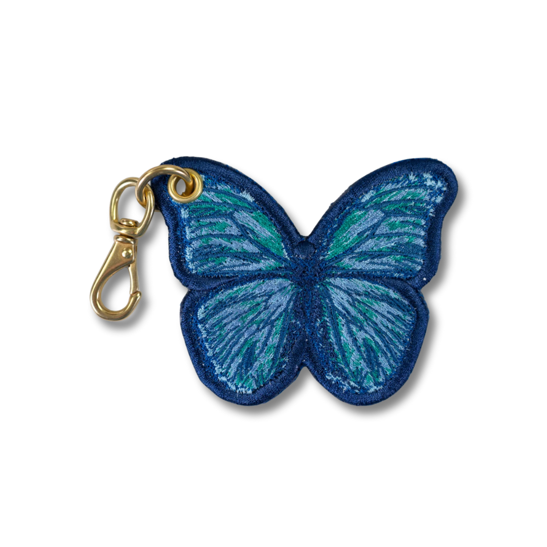 A blue and green embroidered butterfly key charm with a gold-tone lobster clasp, shown on a plain white background.