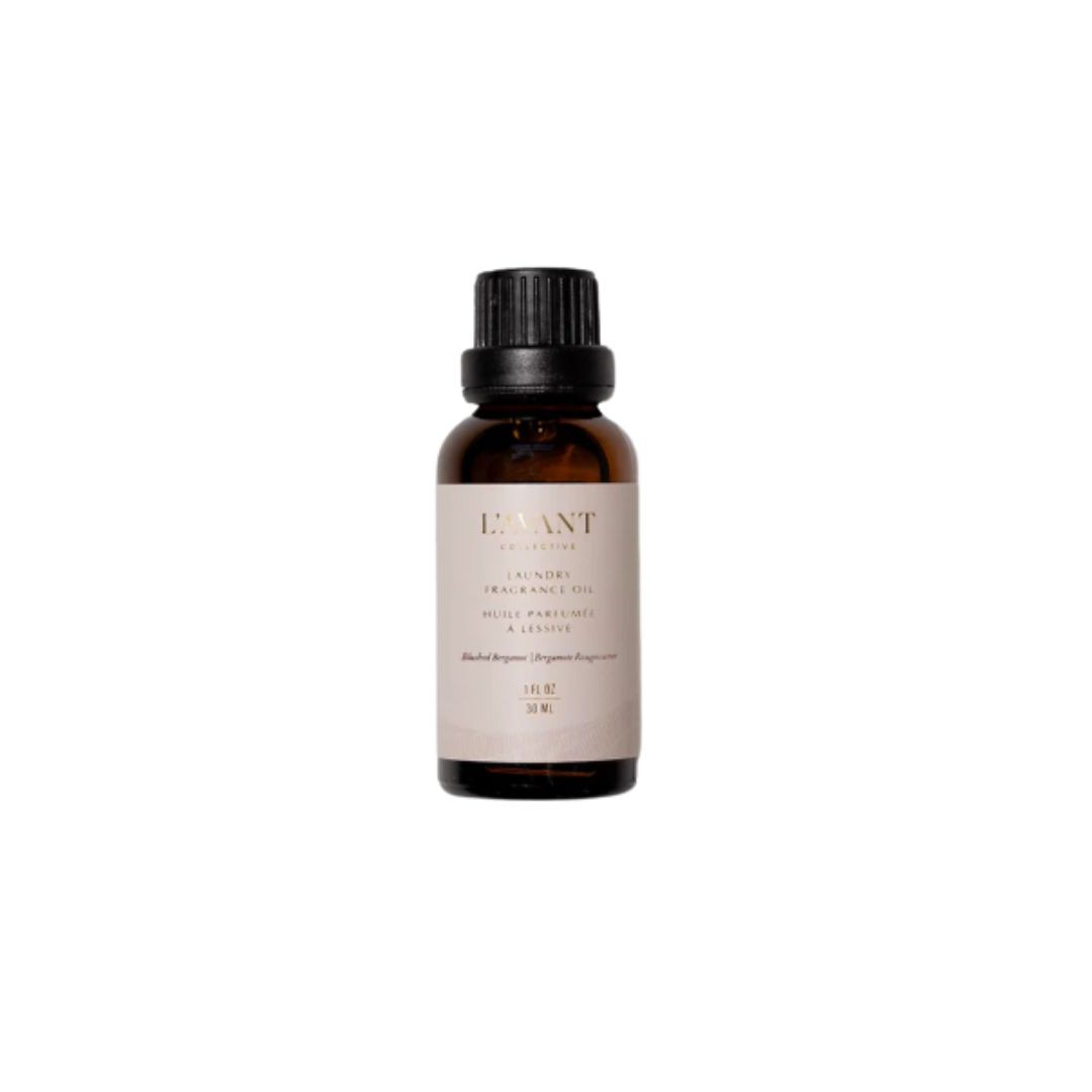 Gold and white L'avant laundry oil bottle with brand name on a beige background