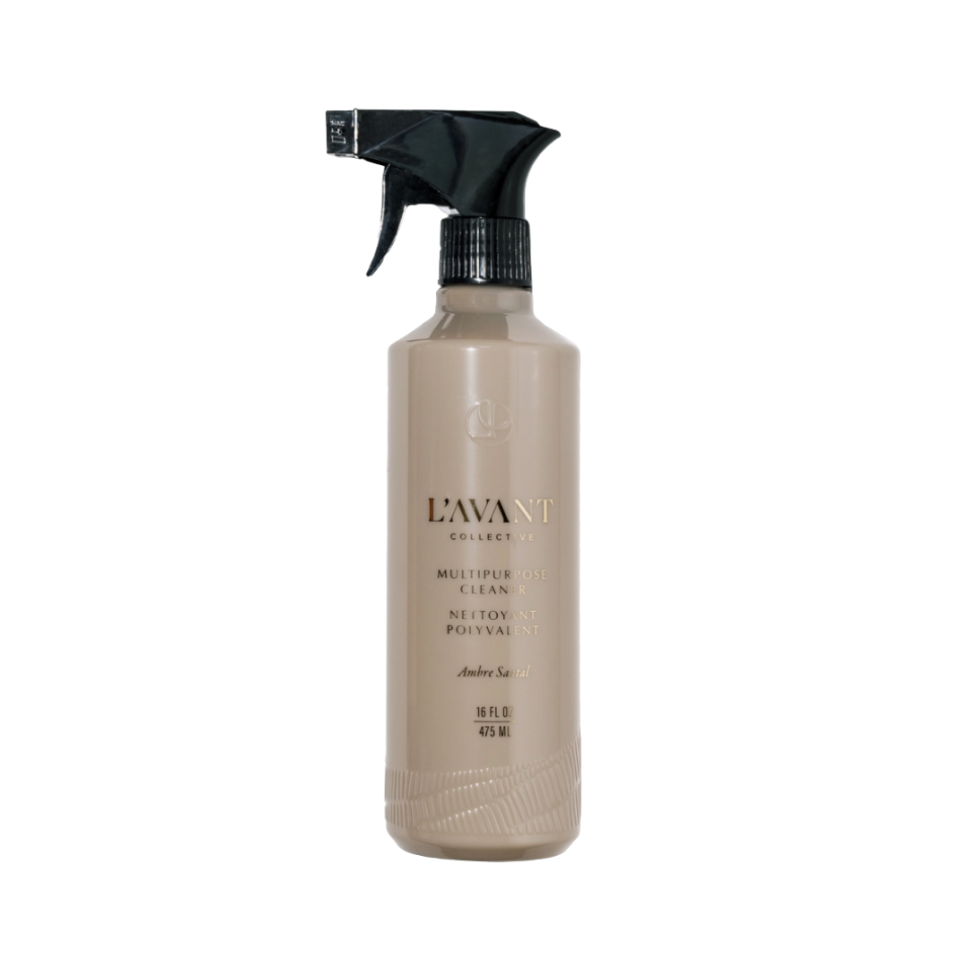 A bottle of L'Avant Collective Multipurpose  Cleaner in Amber Shade, featuring a beige bottle and a black spray nozzle, set against a plain white background.