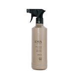 A bottle of L'Avant Collective Multipurpose  Cleaner in Amber Shade, featuring a beige bottle and a black spray nozzle, set against a plain white background.