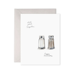 Greeting card with salt and pepper shakers illustration and text 'Still good together, happy anniversary' on a white background.
