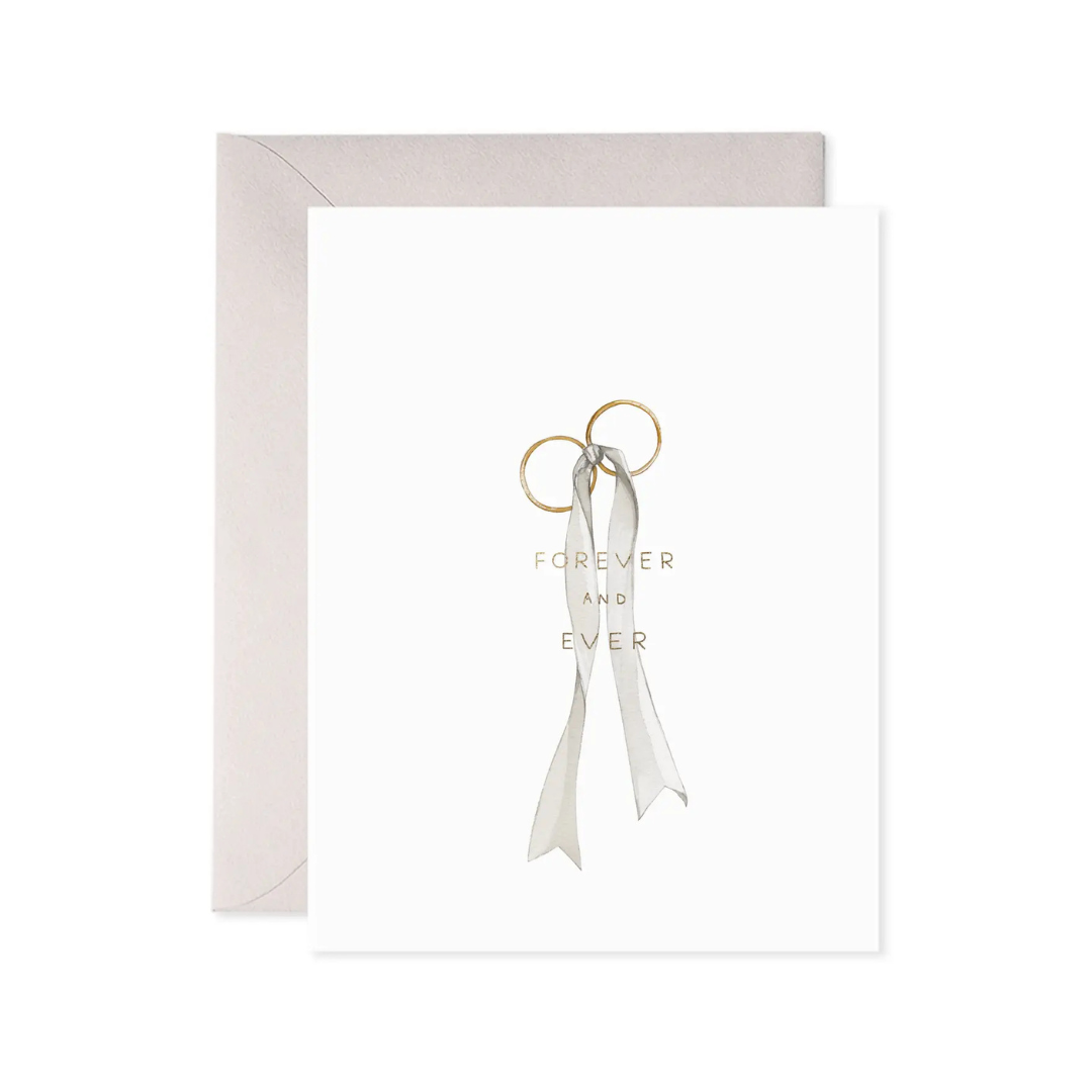 Gold ring with a white ribbon and 'Forever and Ever' text on a light gray background