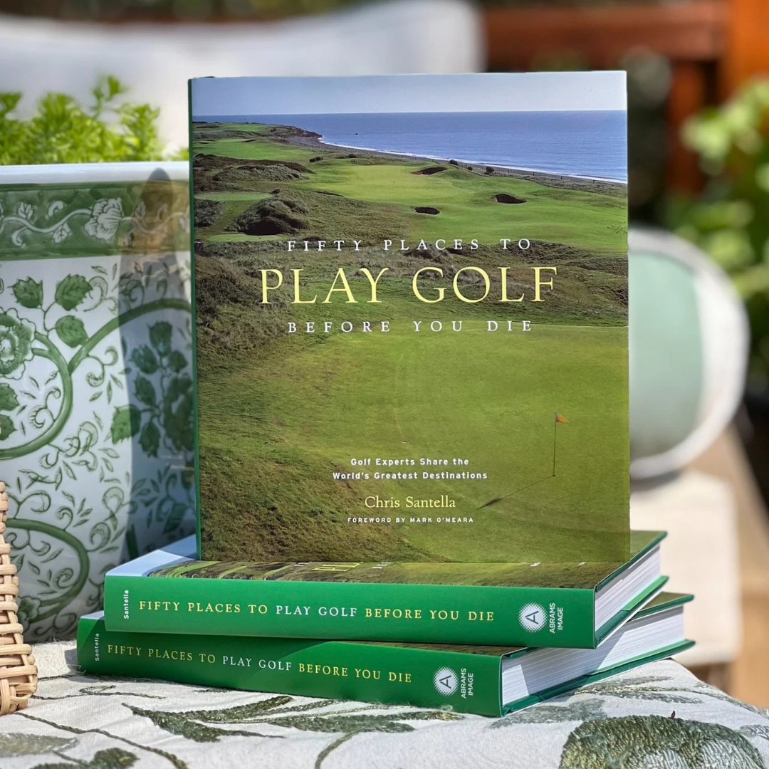 Book titled 'Fifty Places to Play Golf Before You Die' on a table with a golf course background