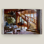 Staircase and living room interior with wooden staircase, table, and chairs.