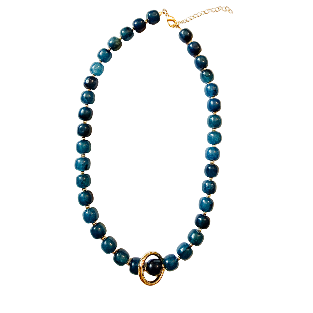 A beaded necklace featuring round dark blue and teal beads with a gold-tone accent ring and clasp, displayed on a clean white background.