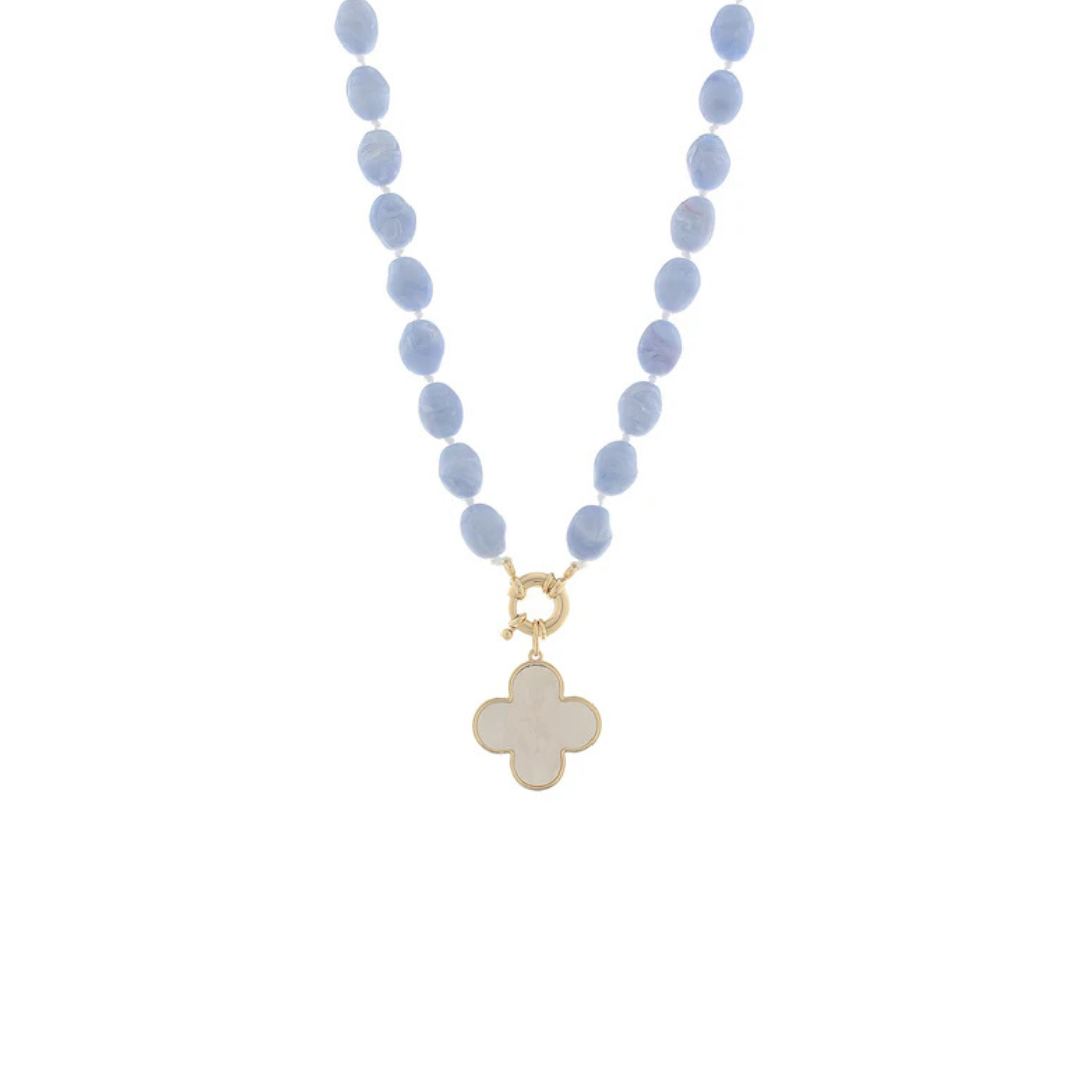 A beaded necklace featuring light blue oval beads and a gold-tone clasp with a white clover-shaped pendant, shown against a plain white background.