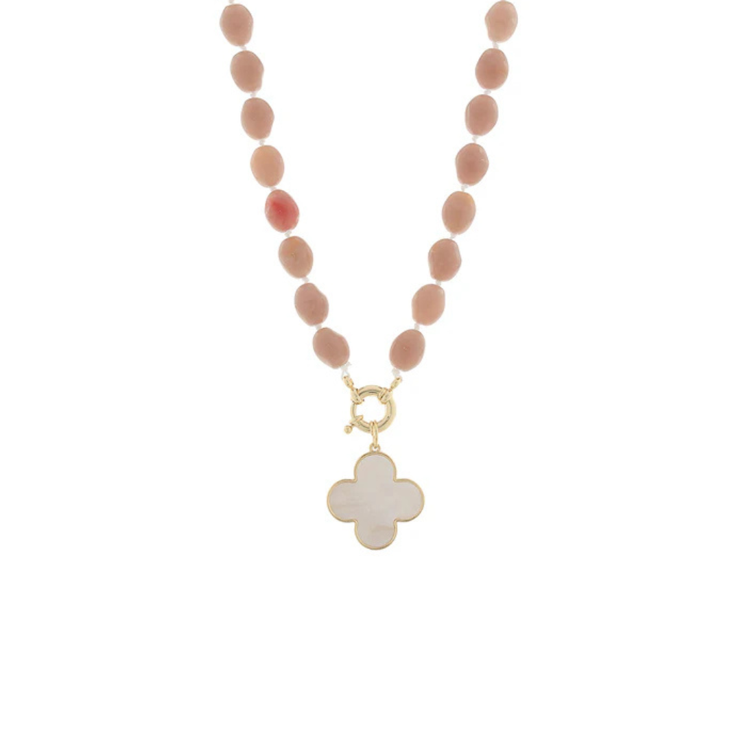 A beaded necklace featuring matte dusty pink oval beads and a gold-tone clasp with a white mother-of-pearl four-leaf clover pendant, shown on a plain white background.