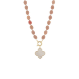 A beaded necklace featuring matte dusty pink oval beads and a gold-tone clasp with a white mother-of-pearl four-leaf clover pendant, shown on a plain white background.