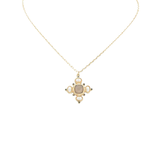 A delicate gold chain necklace featuring a small cross-shaped pendant with a central oval stone and surrounding circular details, displayed against a solid white background.