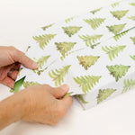 Person folding a piece of paper with green leaf pattern
