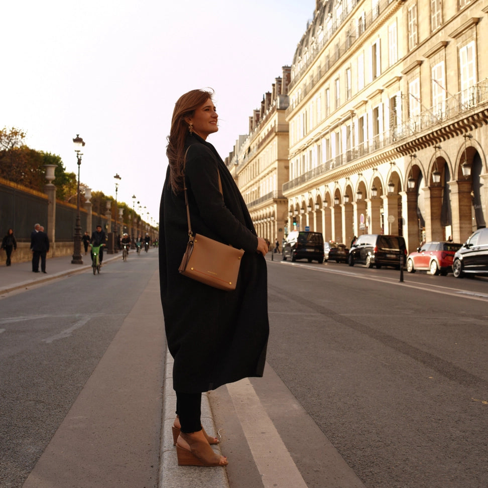 Woman standing on a street in an urban setting with classical architecture wearing Montemare's Vienna Crossbody