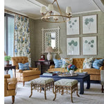Living room with brown sofa, armchair, and ottomans with decorative pillows.