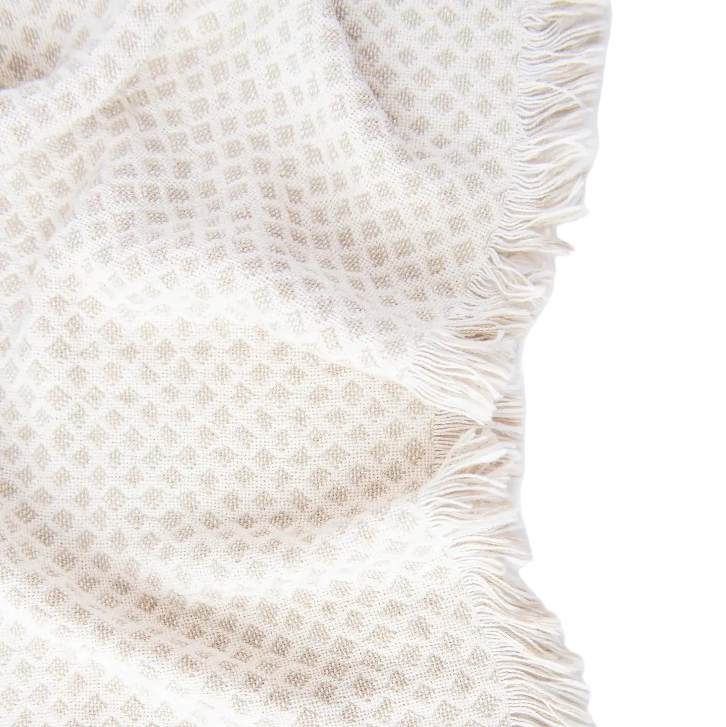 Textured beige blanket with frayed edge on a white background
