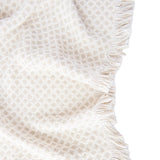 Textured beige blanket with frayed edge on a white background