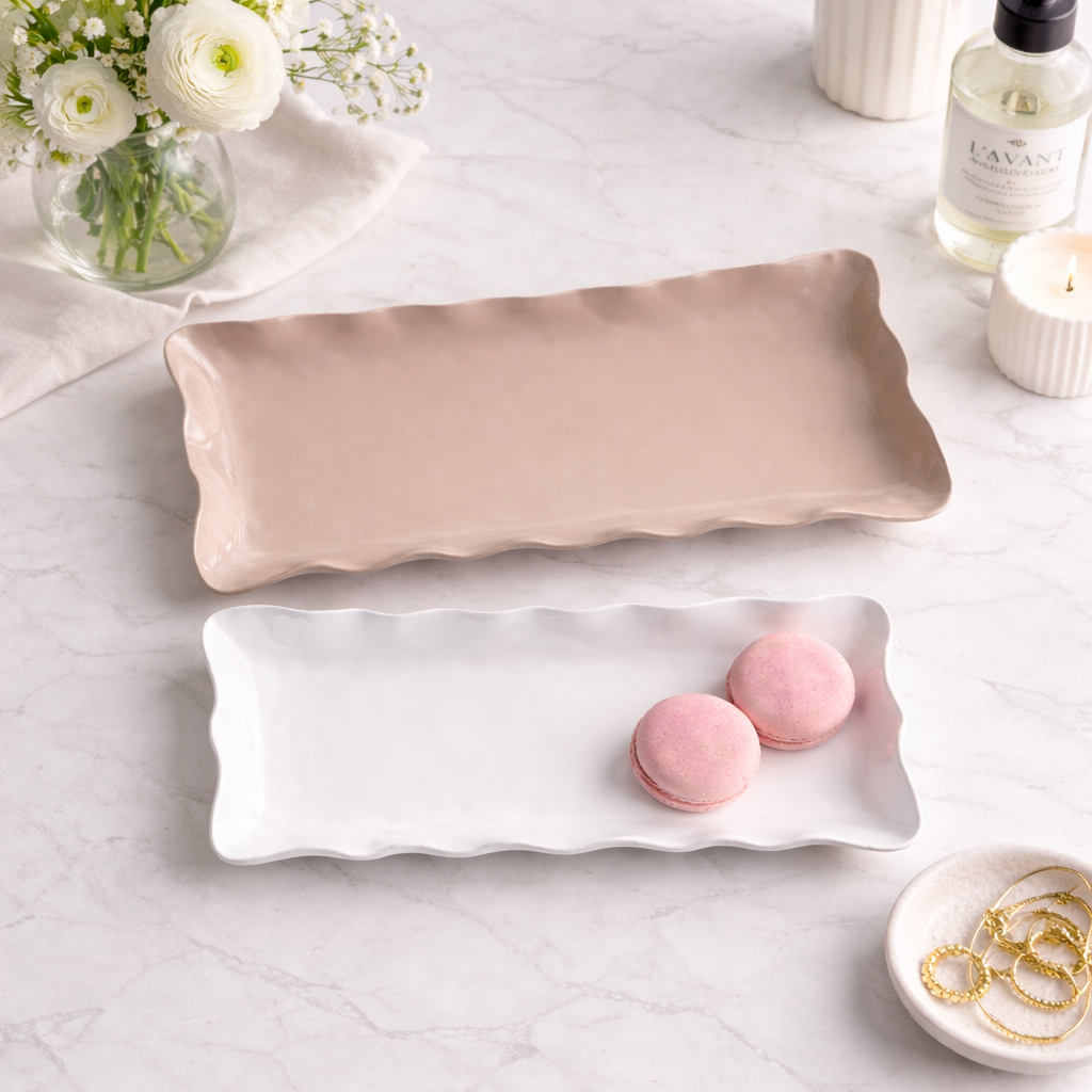 Rectangular beige enamel tray on a white surface with pink macarons, flowers, and a bottle of Lavera product.