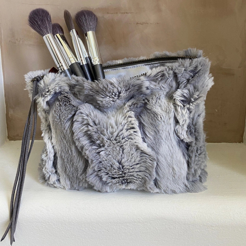 Gray fluffy makeup bag with brushes on a beige background