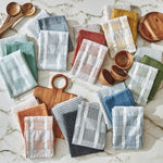 Collection of patterned dishtowels and wooden bowls on a marble surface