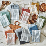 Collection of patterned dishtowels and wooden bowls on a marble surface