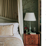 Bedroom with canopy bed and wooden nightstand, featuring a lamp and decorative items.